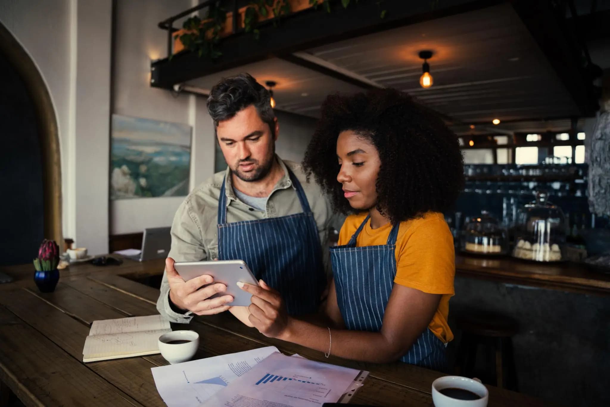 Concerned cafe owners in aprons reviewing a tablet to resolve a Florida missed annual report penalty.
